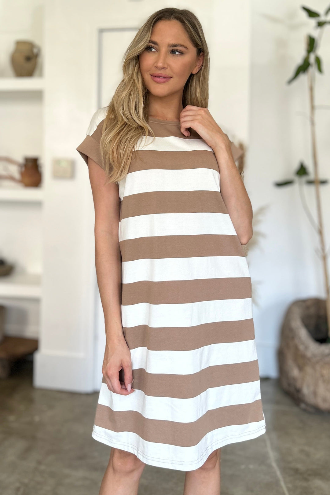 Woman wearing a brown and white striped dress indoors.