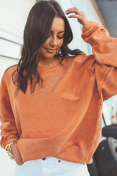 Orange ribbed corduroy sweatshirt with white pants