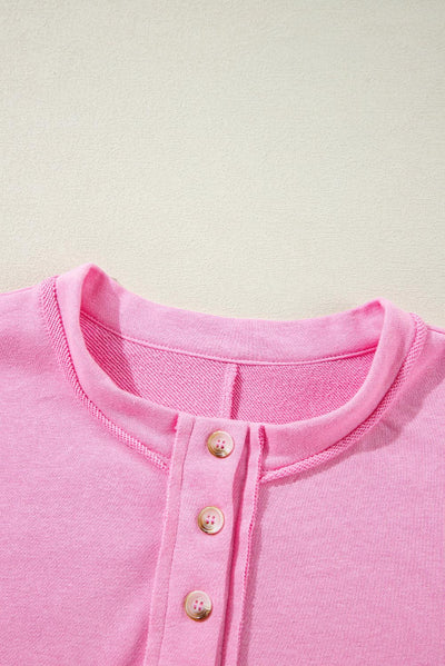 Detail of buttoned neckline on sachet pink sweatshirt