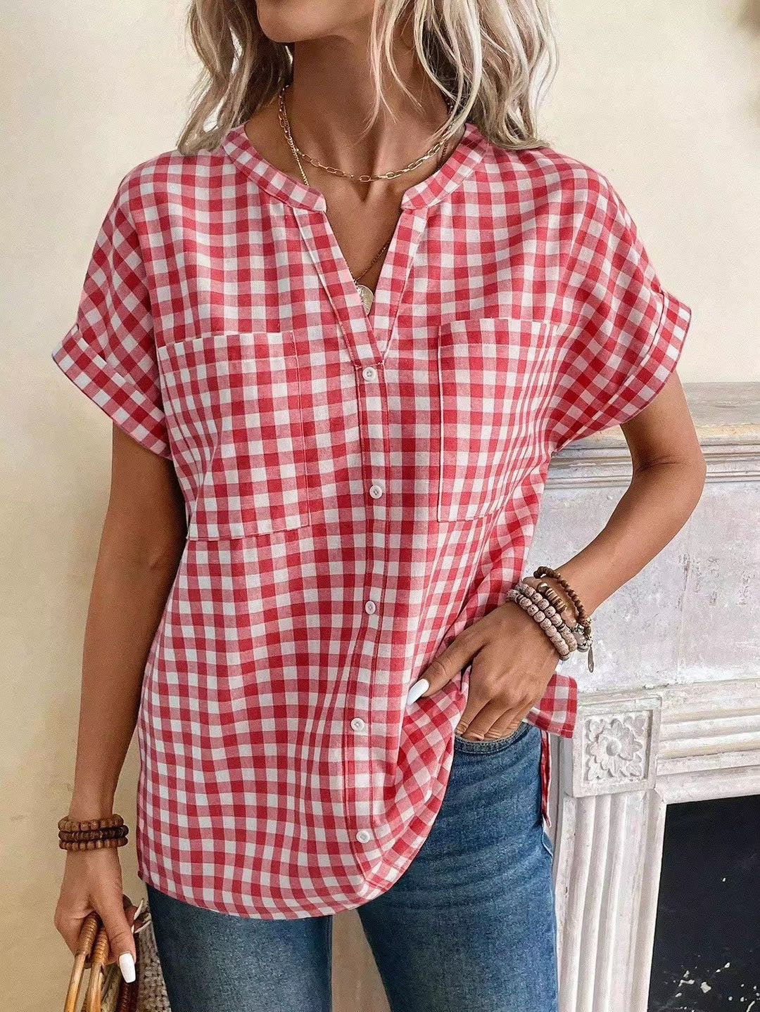 Woman wearing a red and white checkered shirt with blue jeans indoors.