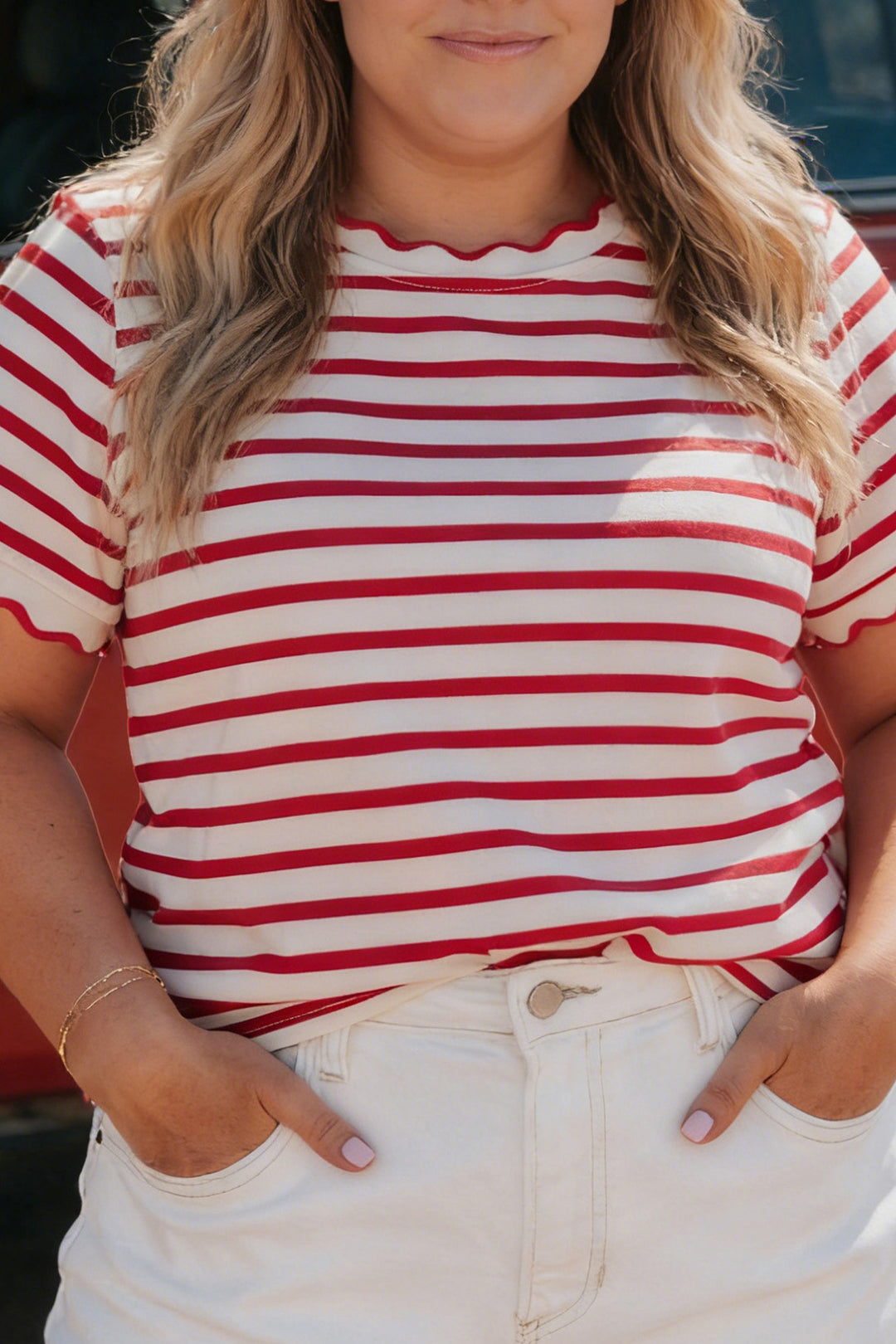 Person wearing a red and white striped shirt with hands in pockets.