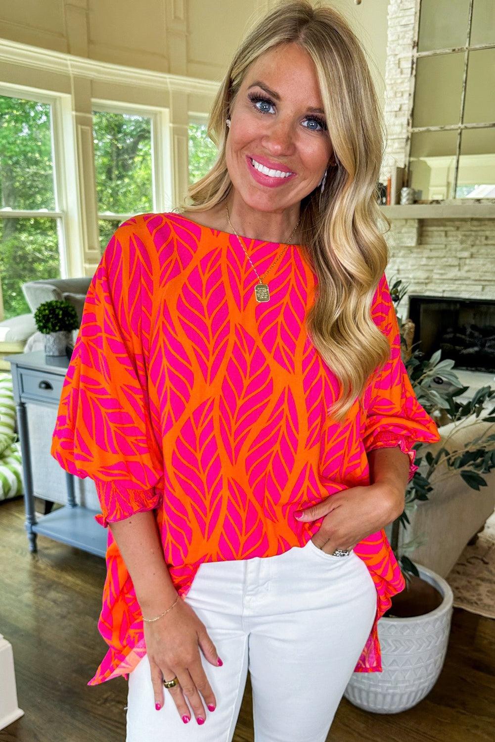 Model wearing tropical leaf print blouse with white pants