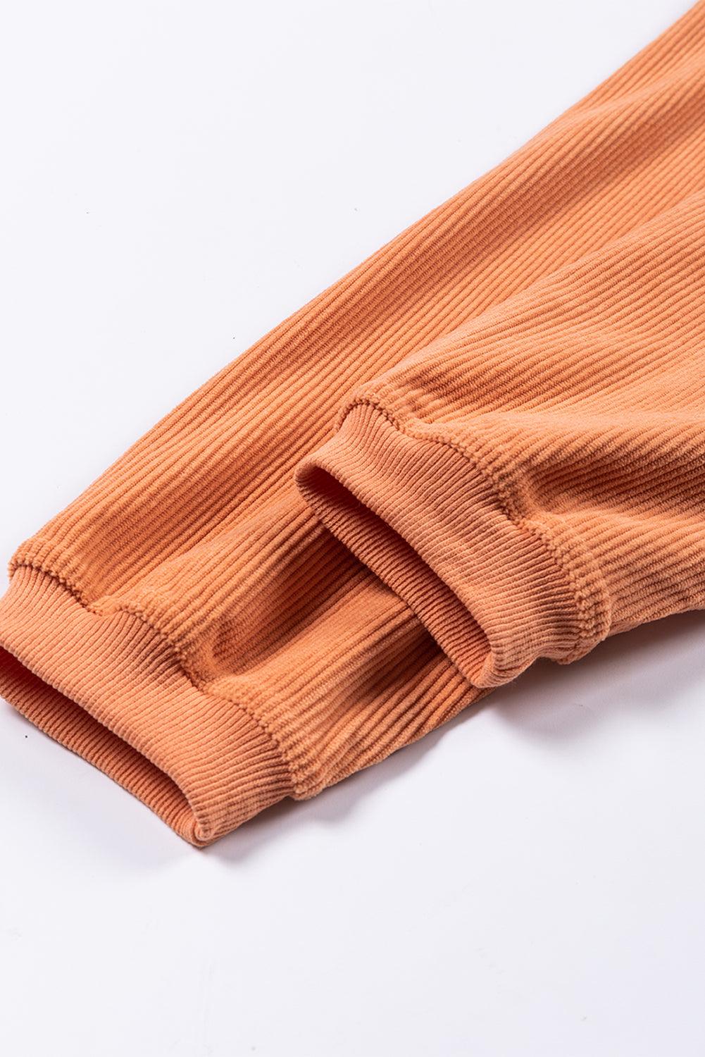 Hem detail of orange ribbed corduroy sweatshirt