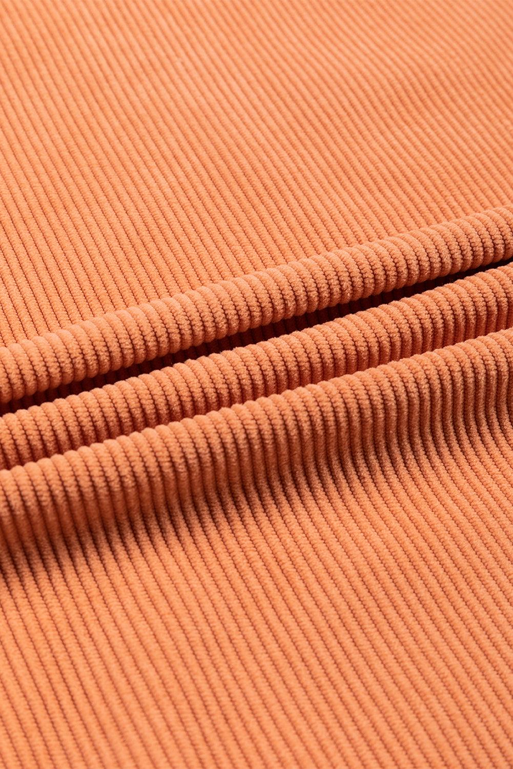 Textured fabric detail of orange ribbed sweatshirt