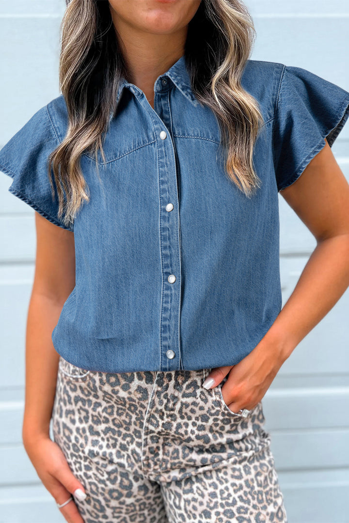 Woman wearing a blue denim shirt with ruffled sleeves and leopard print pants against a light blue background
