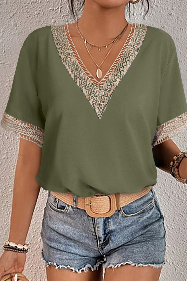 Green top with lace details worn by a person against a plain background