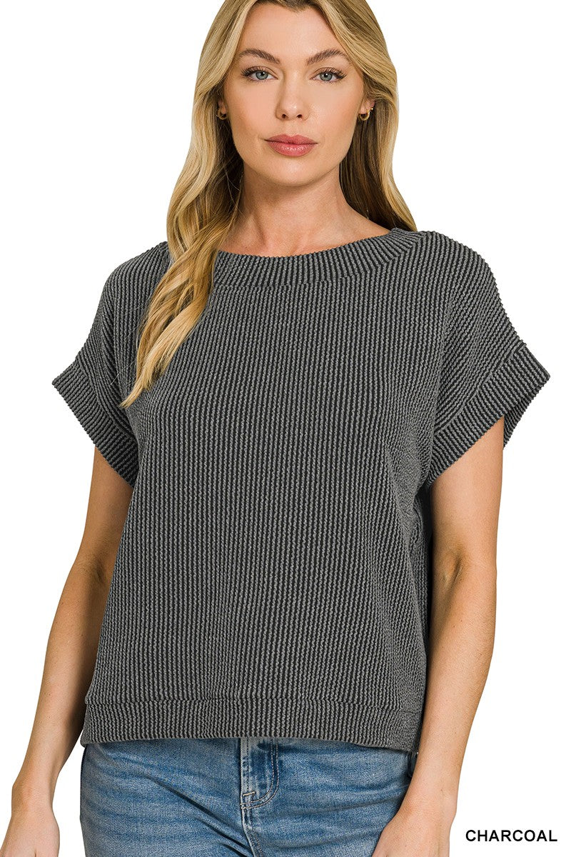 Woman wearing a charcoal ribbed sweater and jeans on a white background