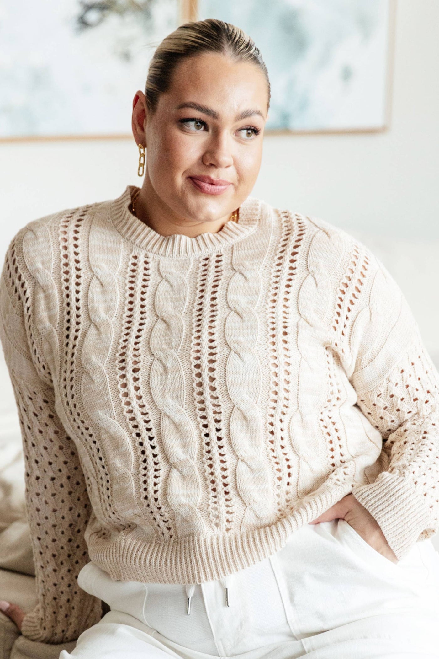 Plus-size model in ivory cable knit sweater, relaxed fit.