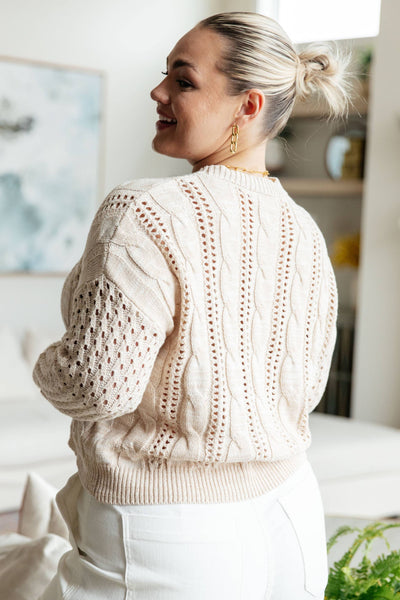 Back view of plus-size model in ivory cable knit sweater.