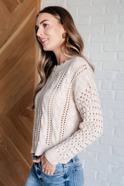 Side profile of model in ivory cable knit sweater.