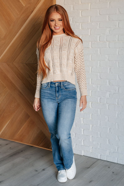 Red-haired model in cable knit sweater and jeans.