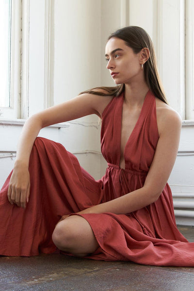 Rust woven maxi dress, seated pose, deep V-neck detail.