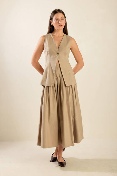 Full view of beige vest and pleated skirt