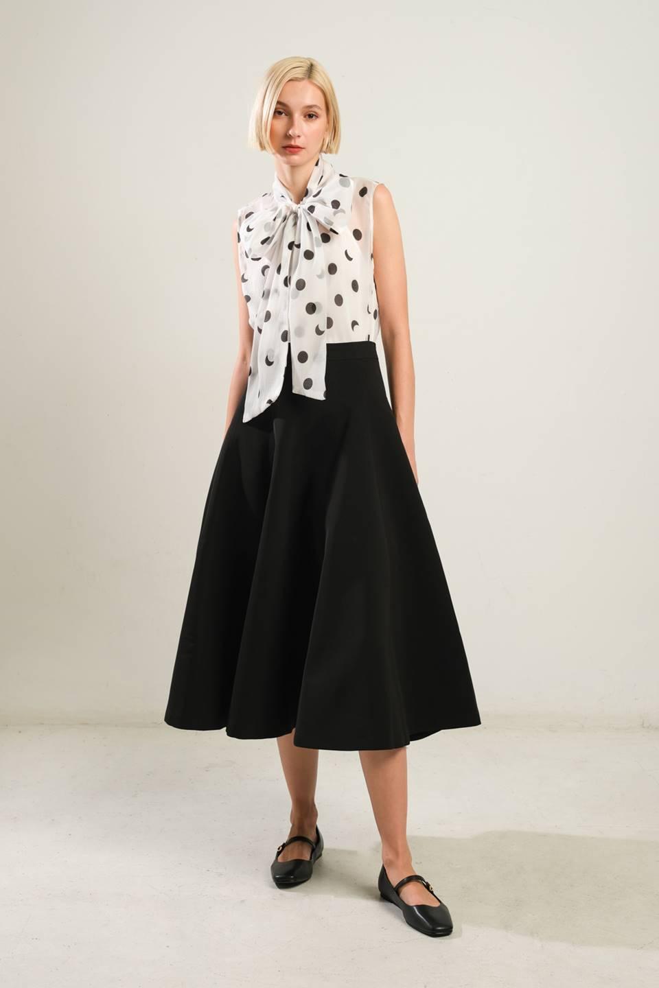 Front view of black woven skirt with polka dot blouse