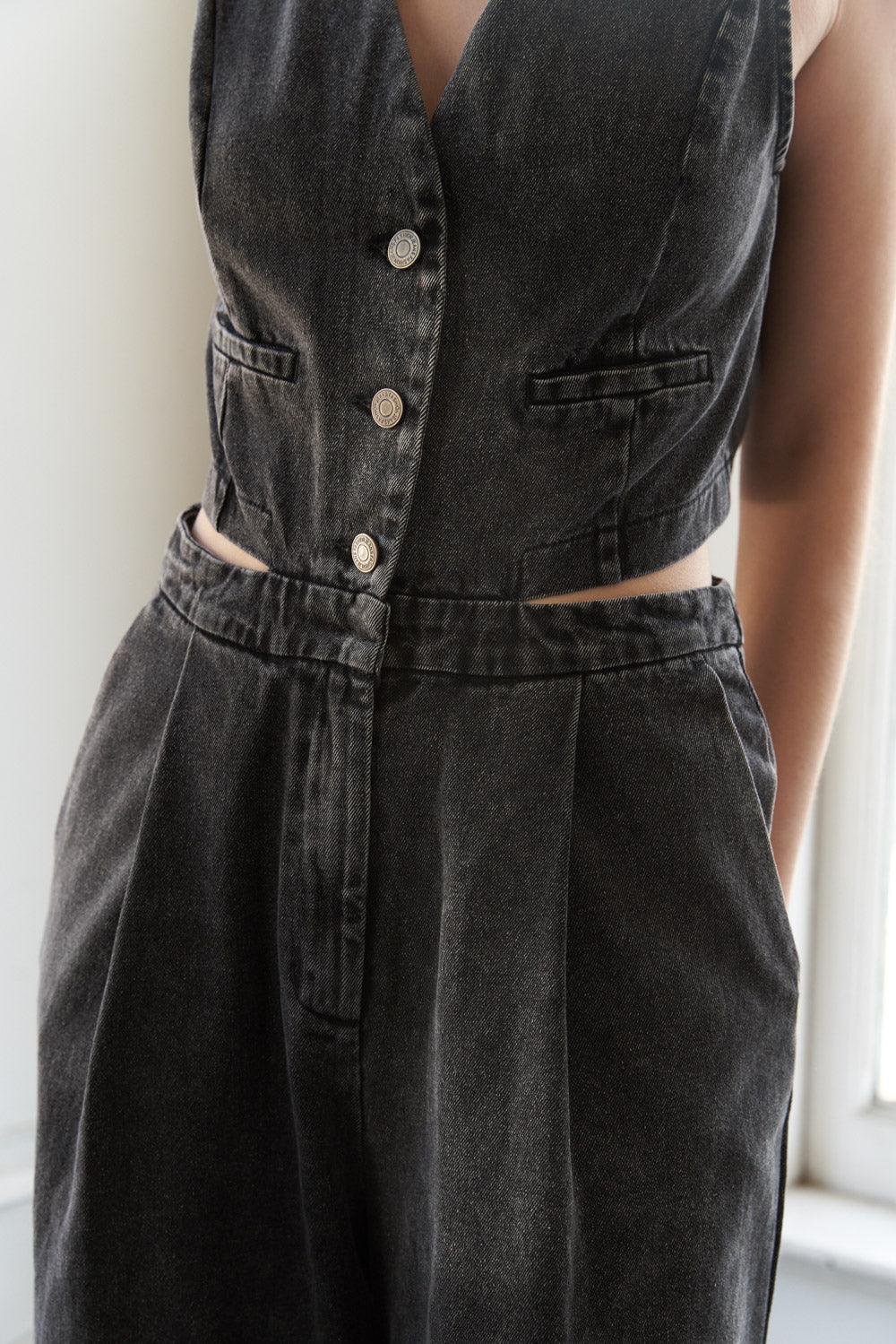 Detail of buttoned front and waist cutout on denim jumpsuit.