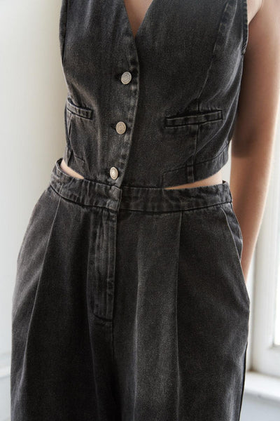 Detail of buttoned front and waist cutout on denim jumpsuit.