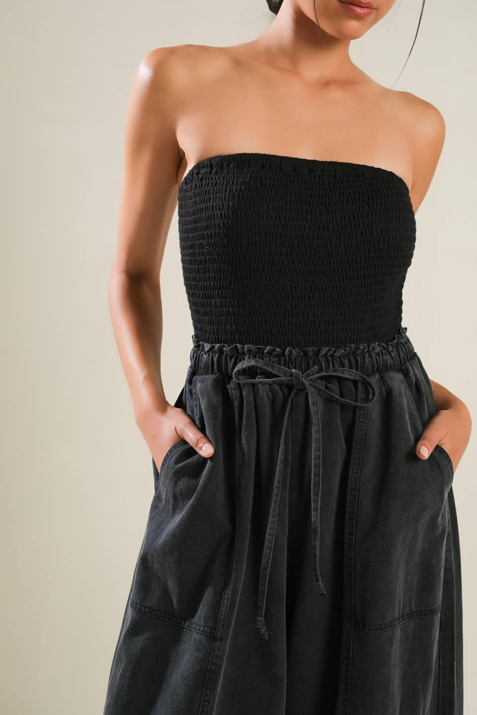 Close-up of black strapless jumpsuit with drawstring waist.