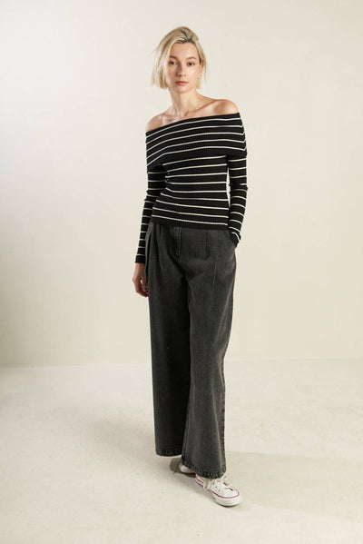 Full body view of black and white striped off-shoulder sweater