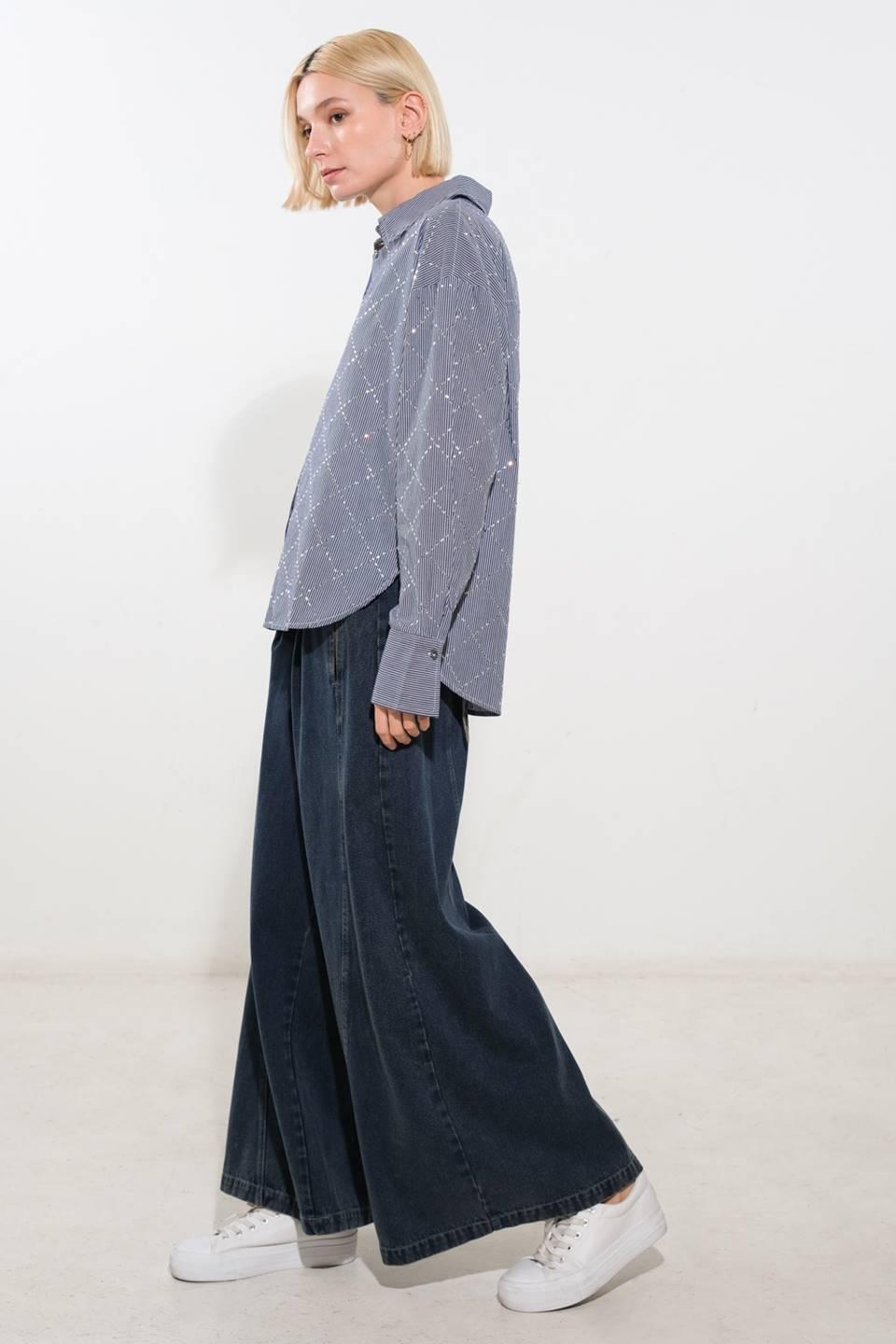 Side view of navy and white woven top paired with wide-leg jeans.