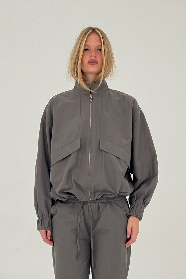 Person wearing a gray tracksuit on a white background