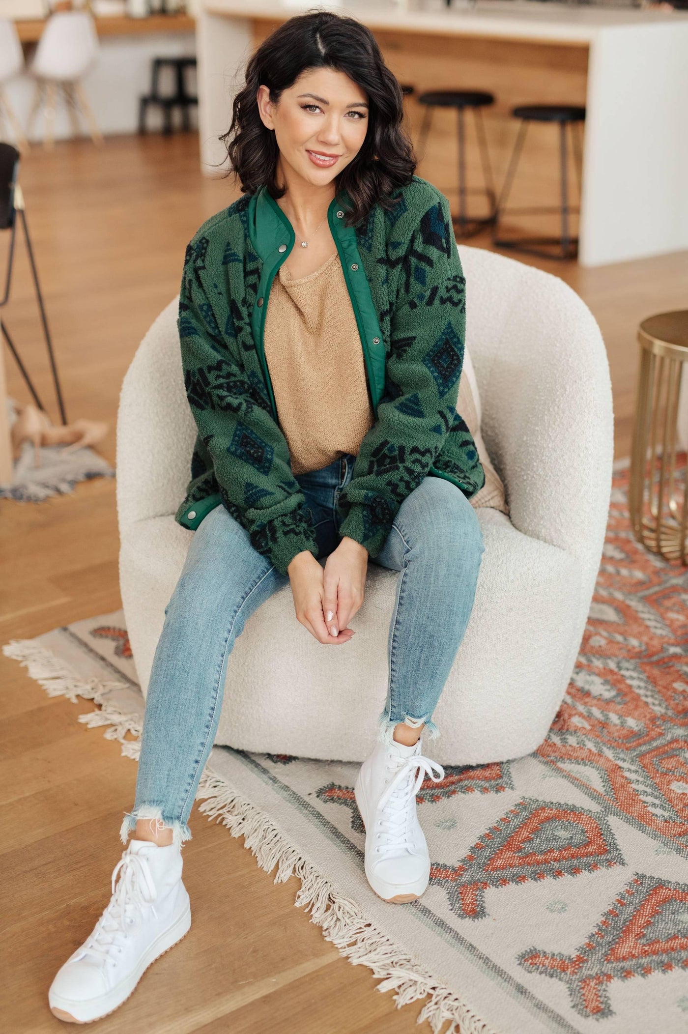 Model seated in green geometric fleece jacket