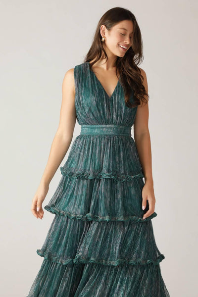 Model wearing teal green pleated maxi dress, smiling.