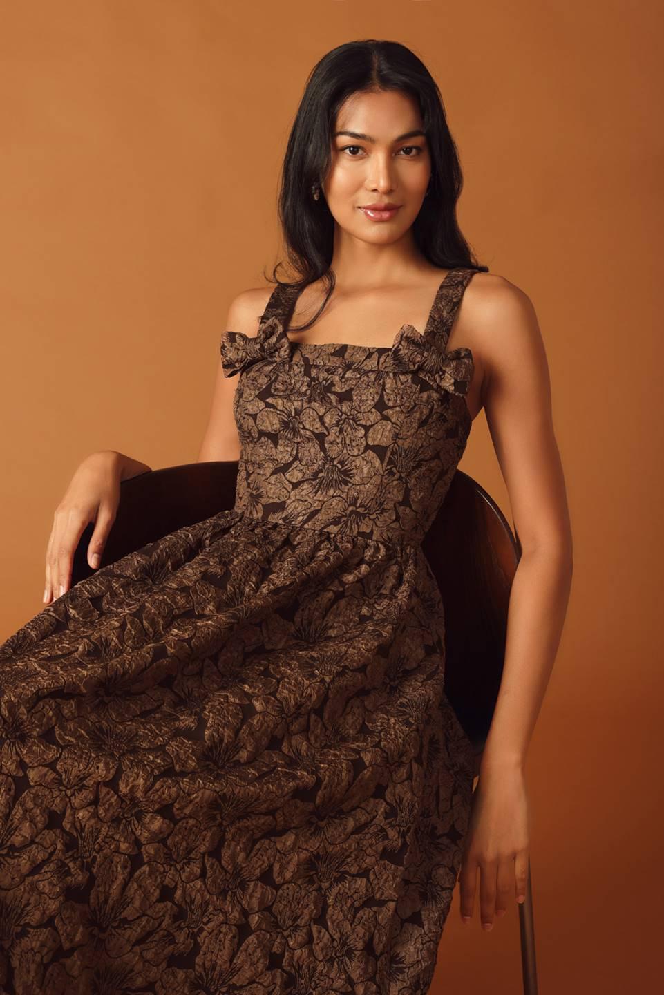 Seated model in brown woven midi dress, floral design