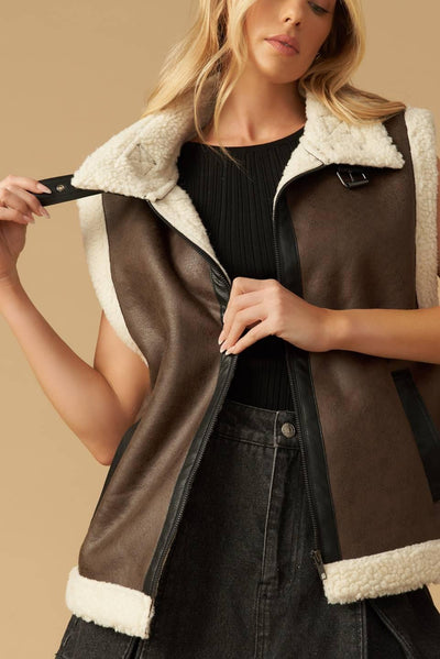 Model adjusting brown leather vest with shearling trim