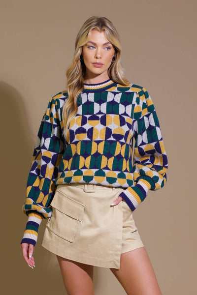 Model wearing geometric jacquard sweater with beige skirt