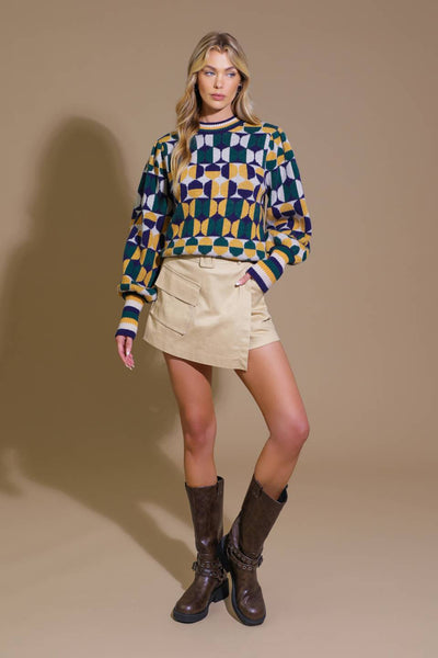 Model in geometric jacquard sweater and boots, front view