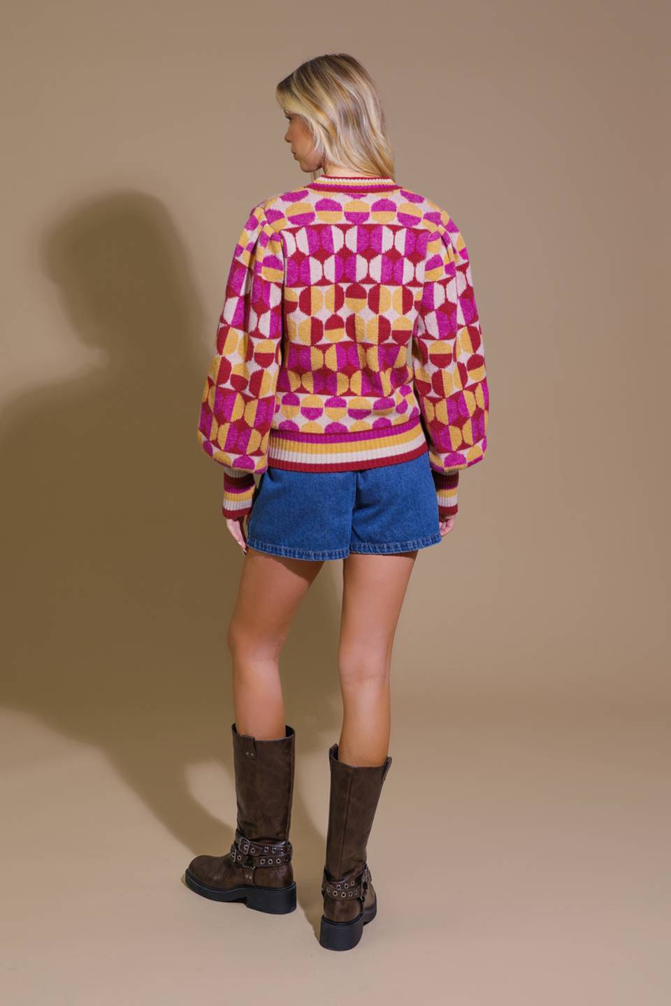 Back view of pink and orange sweater with denim shorts and boots