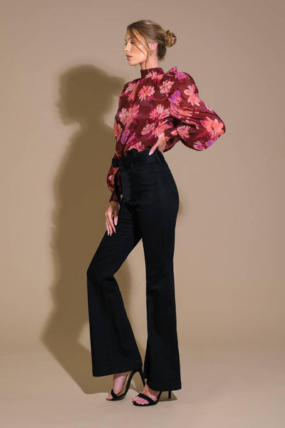 Side view of burgundy floral woven top with black pants