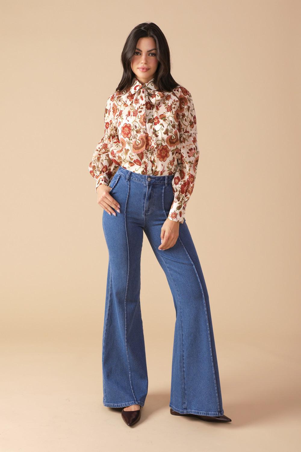 Model posing in ivory floral blouse and blue jeans