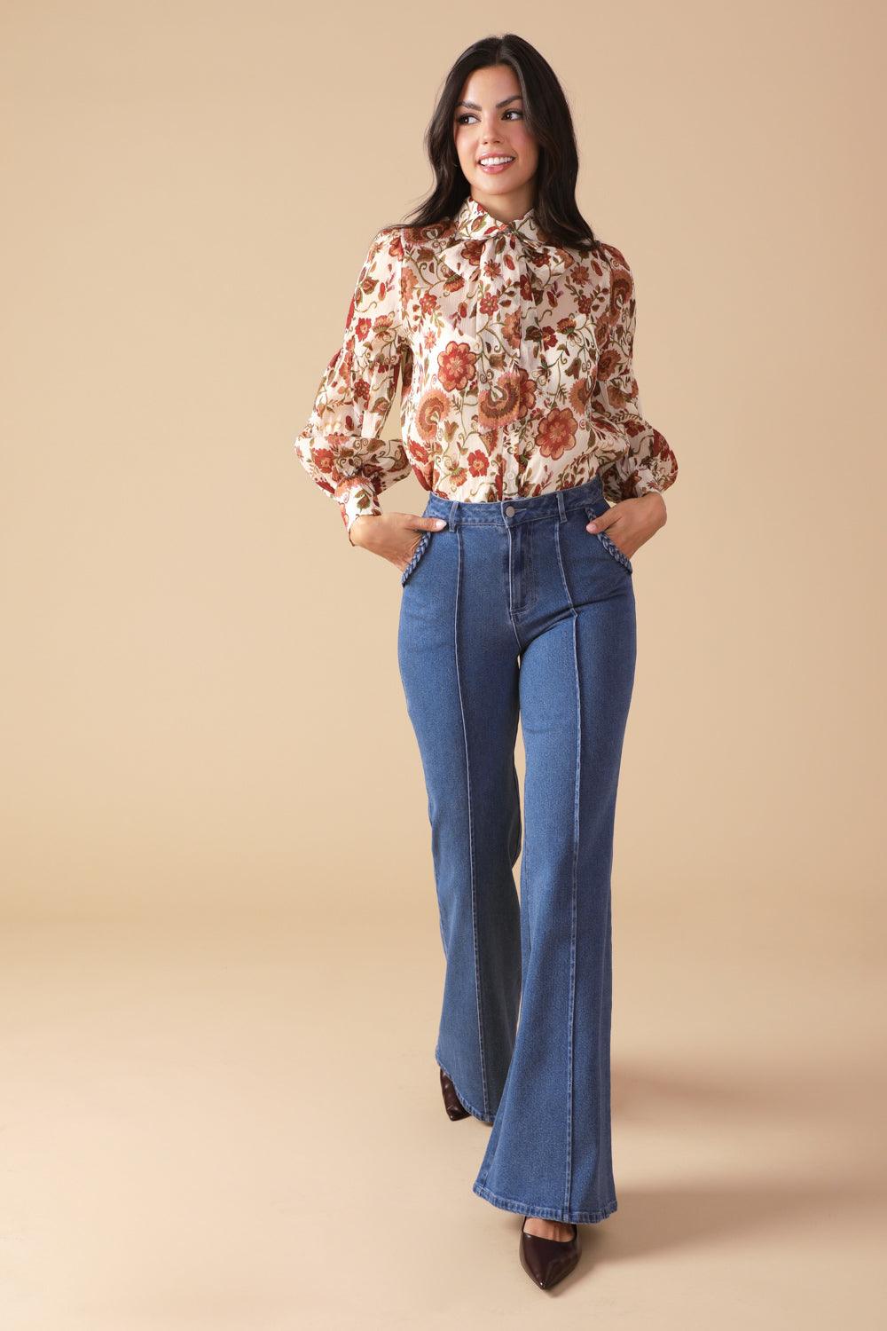 Model in ivory floral blouse and blue jeans, walking