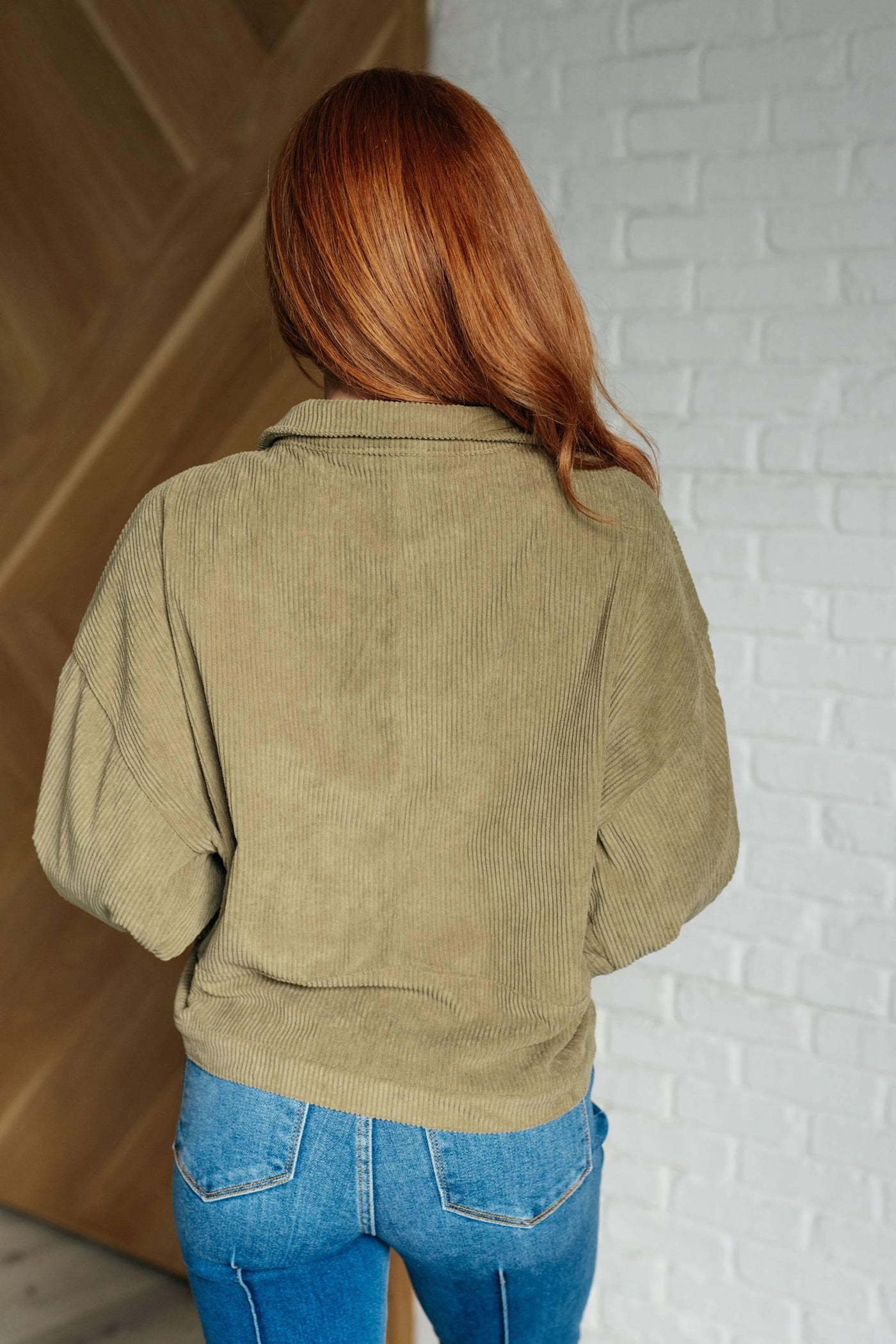 Back view of olive corduroy jacket with blue jeans.