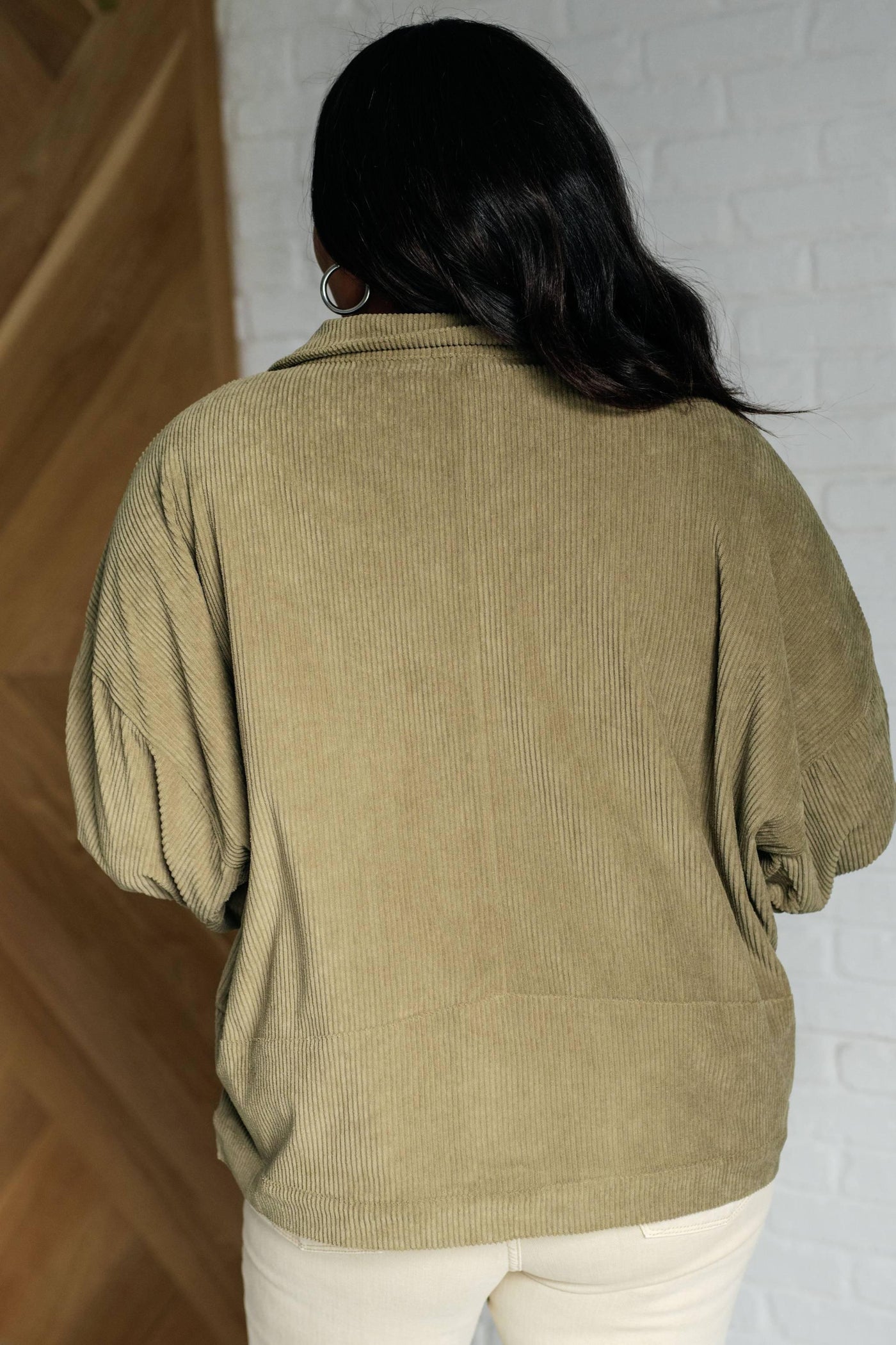 Back view of olive corduroy jacket on model.