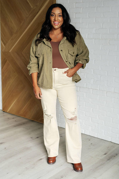 Model in olive corduroy jacket and light ripped jeans.