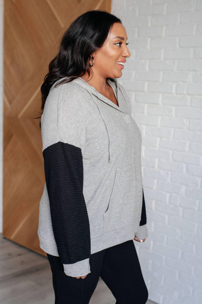 Side view of gray hoodie with black sleeves