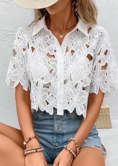 Woman wearing a white lace blouse and denim shorts against a neutral background