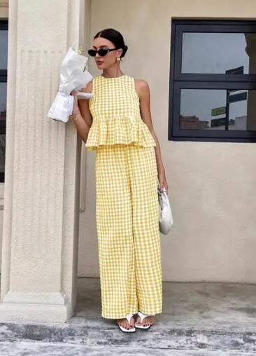 Woman wearing a yellow checkered dress standing outside a building.