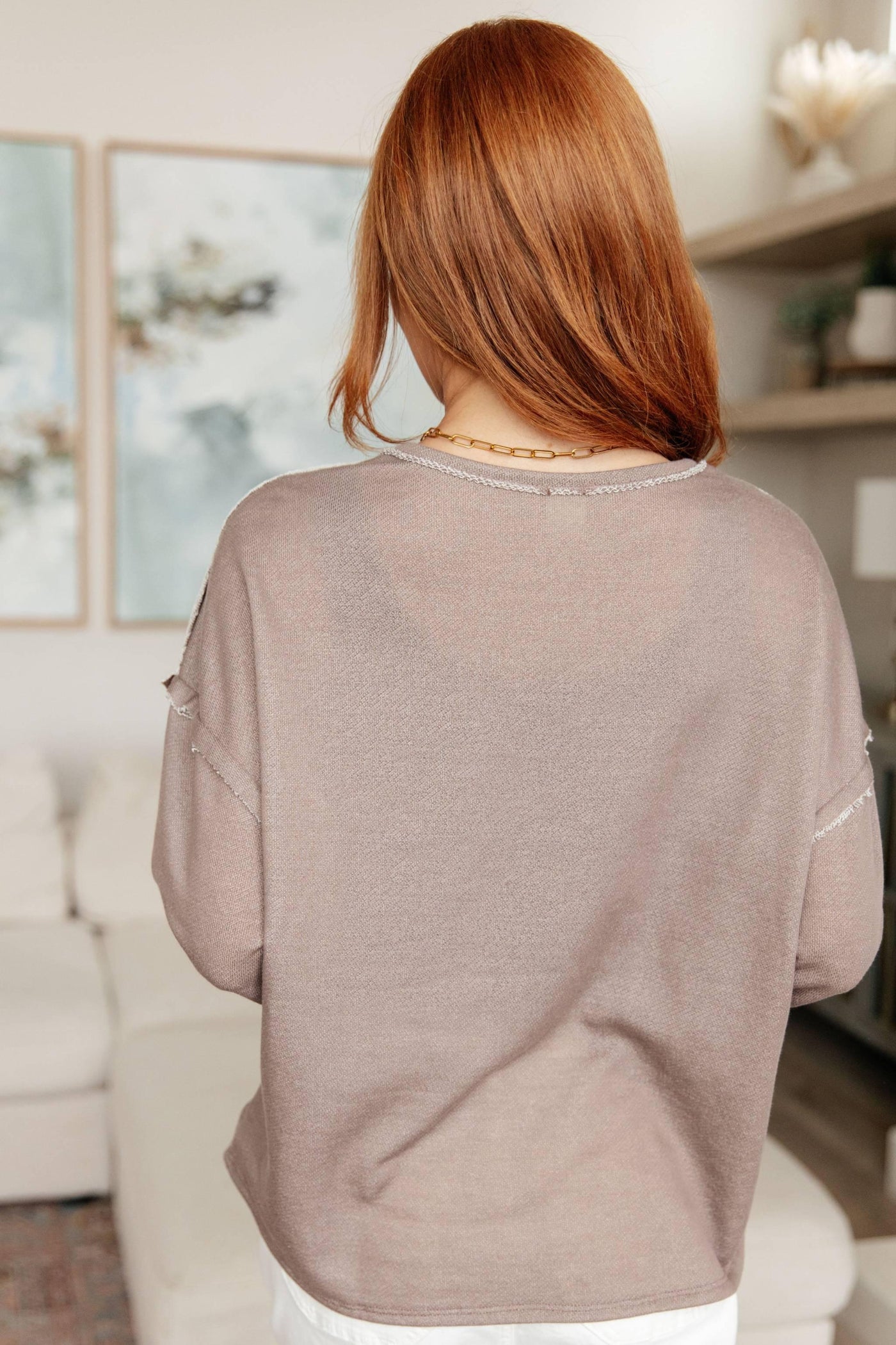 Back view of brown V-neck pullover, worn by model.