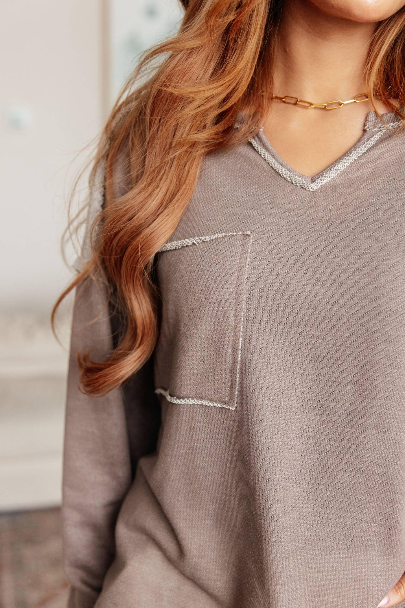 Close-up of pocket and neckline on brown V-neck pullover.