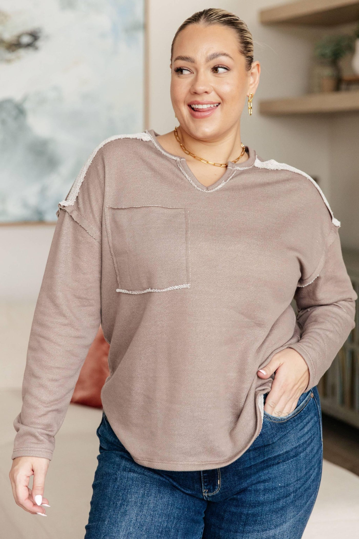 Brown V-neck pullover with pocket, worn by smiling model.