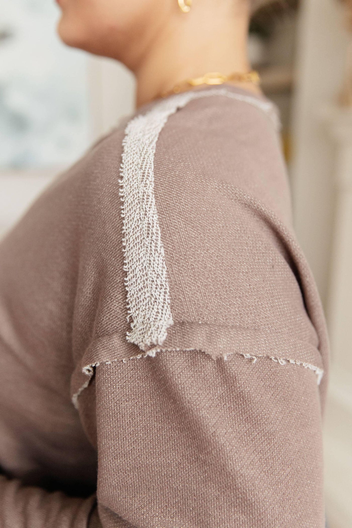 Close-up of shoulder detail on brown V-neck pullover.