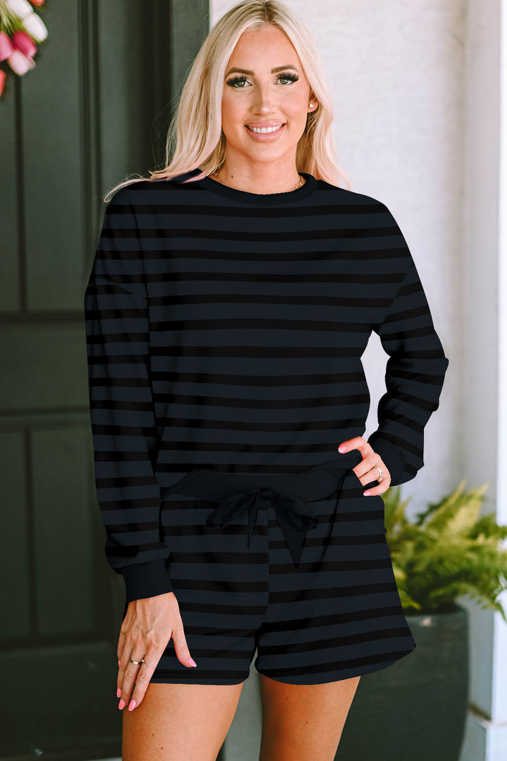 Woman wearing a black striped outfit standing outdoors.