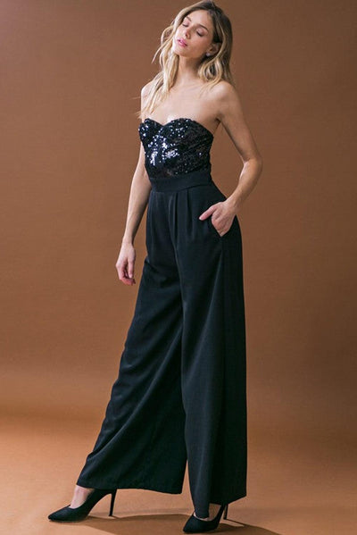 Model posing in black sequin tube top jumpsuit