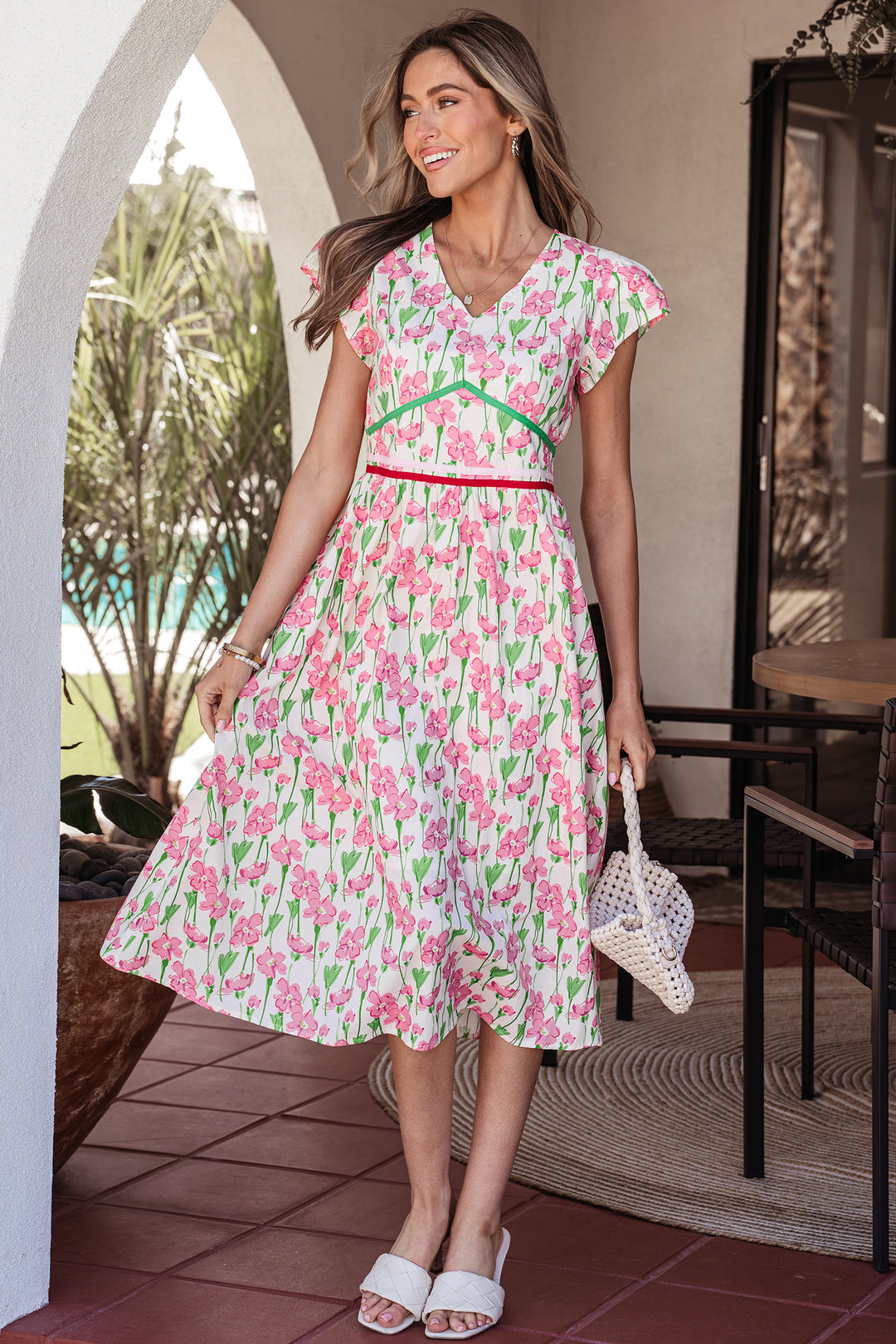 Woman wearing a pink floral dress standing in an outdoor setting.