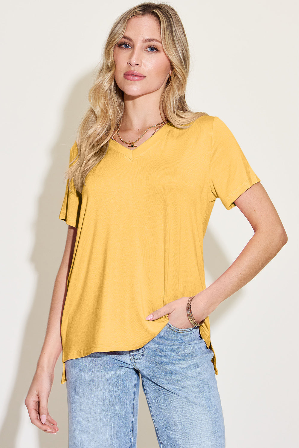 Woman wearing a yellow top and blue jeans against a plain background