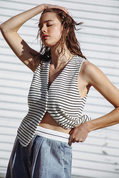 Striped knit vest in cream and black, styled with denim pants.