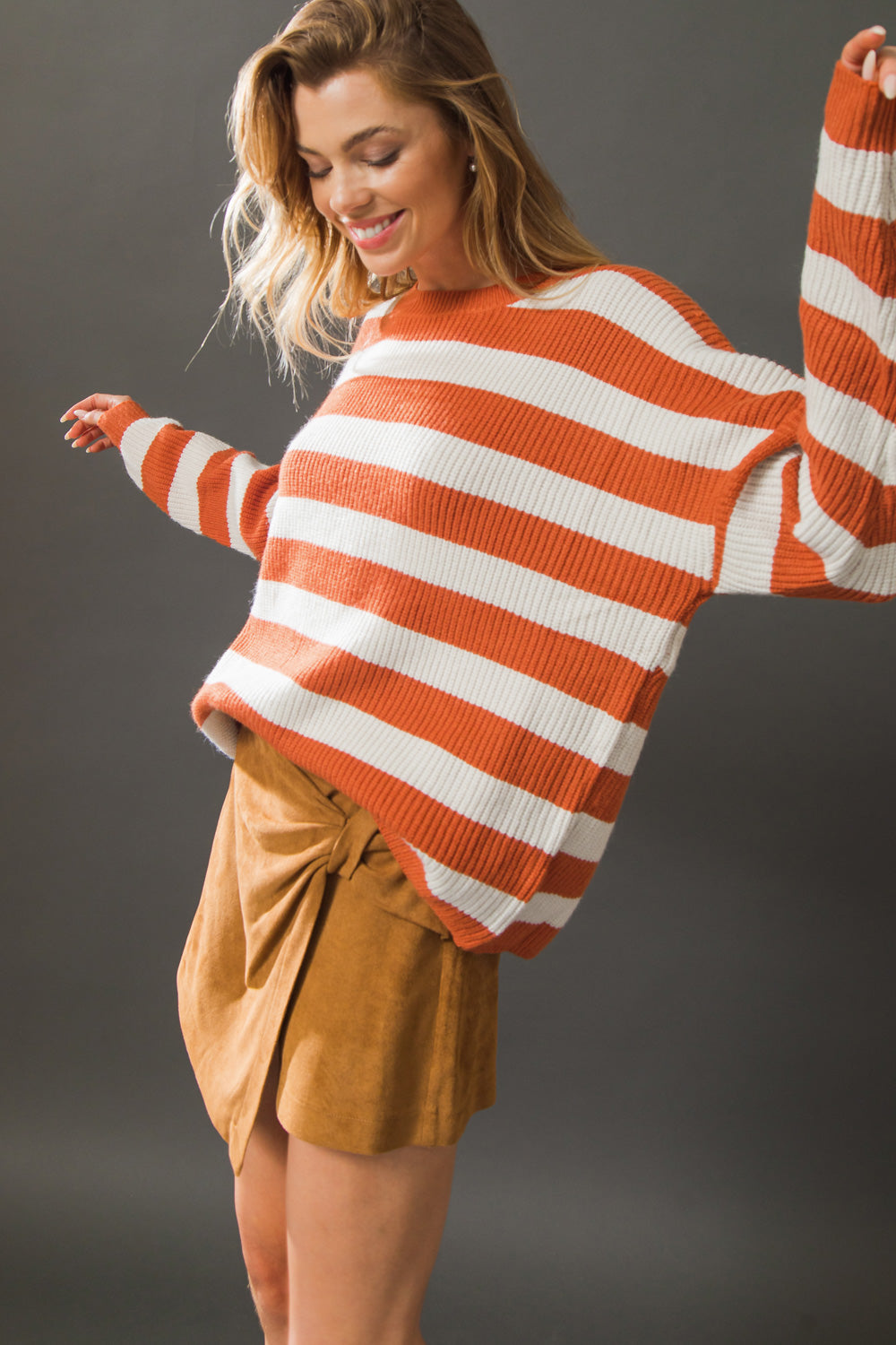 Model twirling in rust and ivory striped sweater top